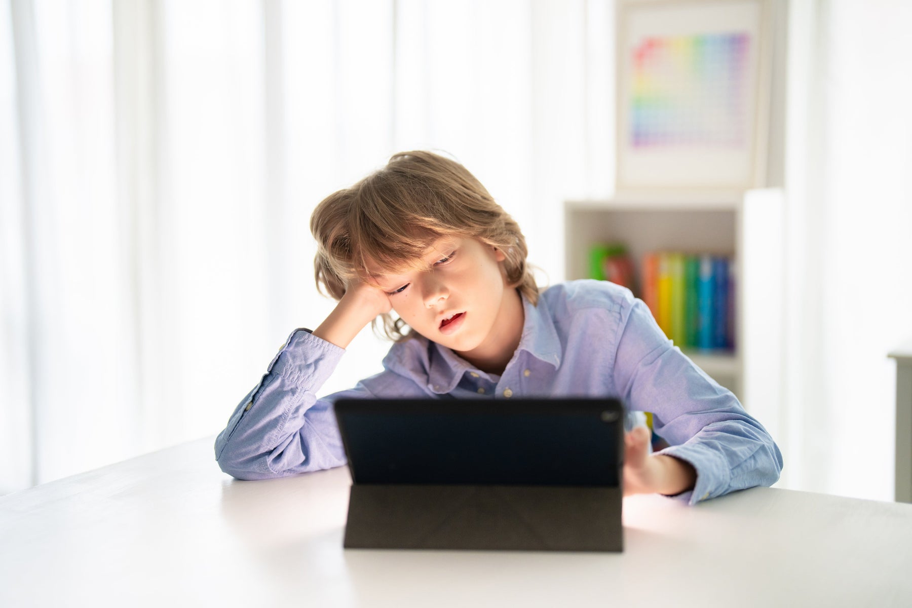 Müder Junge vor einem Tablet, Symbol für zu viel Bildschirmzeit, die Magneo mit kreativem, montessori-inspiriertem STEM-Spielzeug reduzieren hilft.