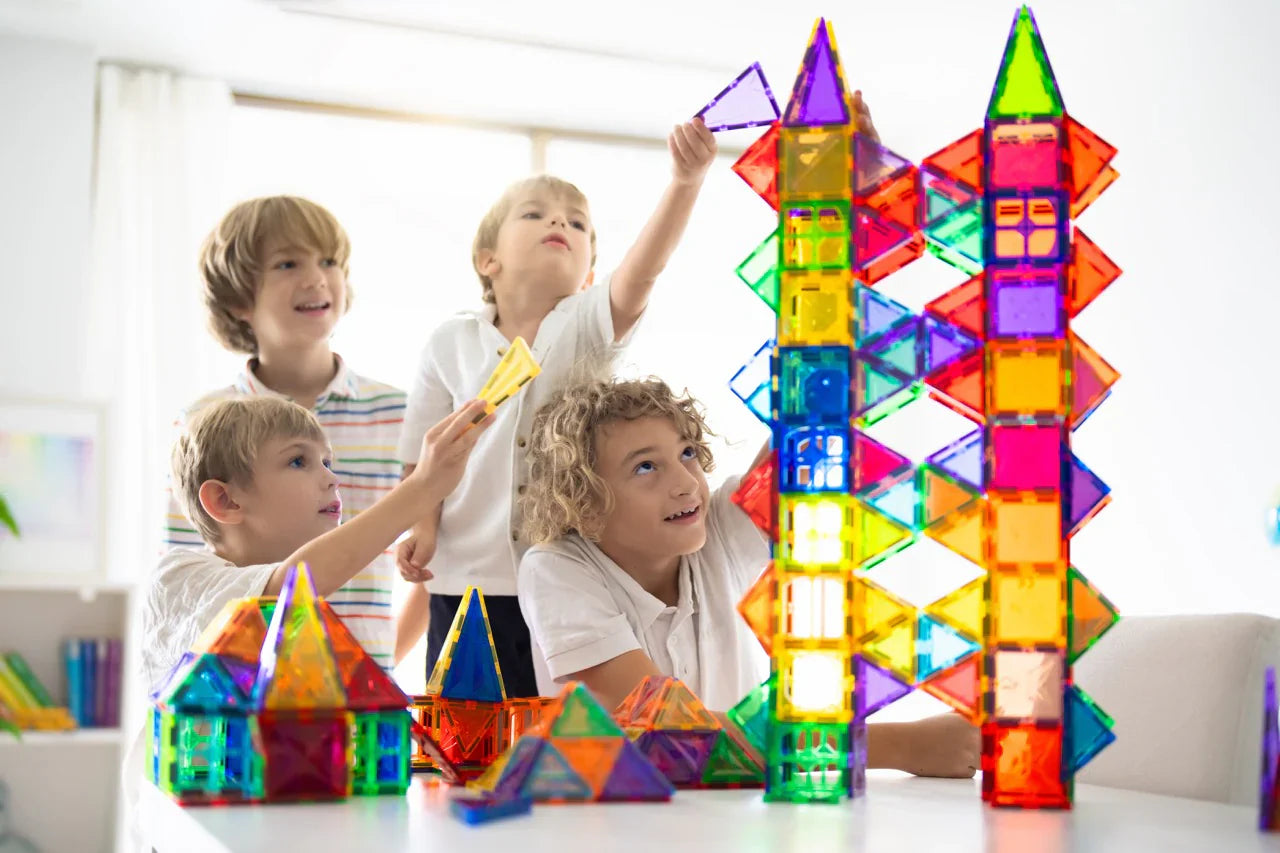 Kinder bauen gemeinsam mit bunten Magnetbausteinen hohe Türme und Häuser, kreatives Montessori Spielzeug ohne Bildschirm, fördert Teamarbeit, Fantasie und räumliches Denken