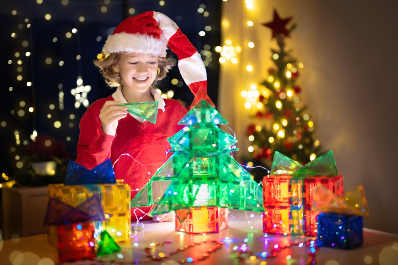 Glückliches Kind entdeckt spielerisch STEM-Lernen mit Magneo Magnetbausteinen auf einer Spielmatte.