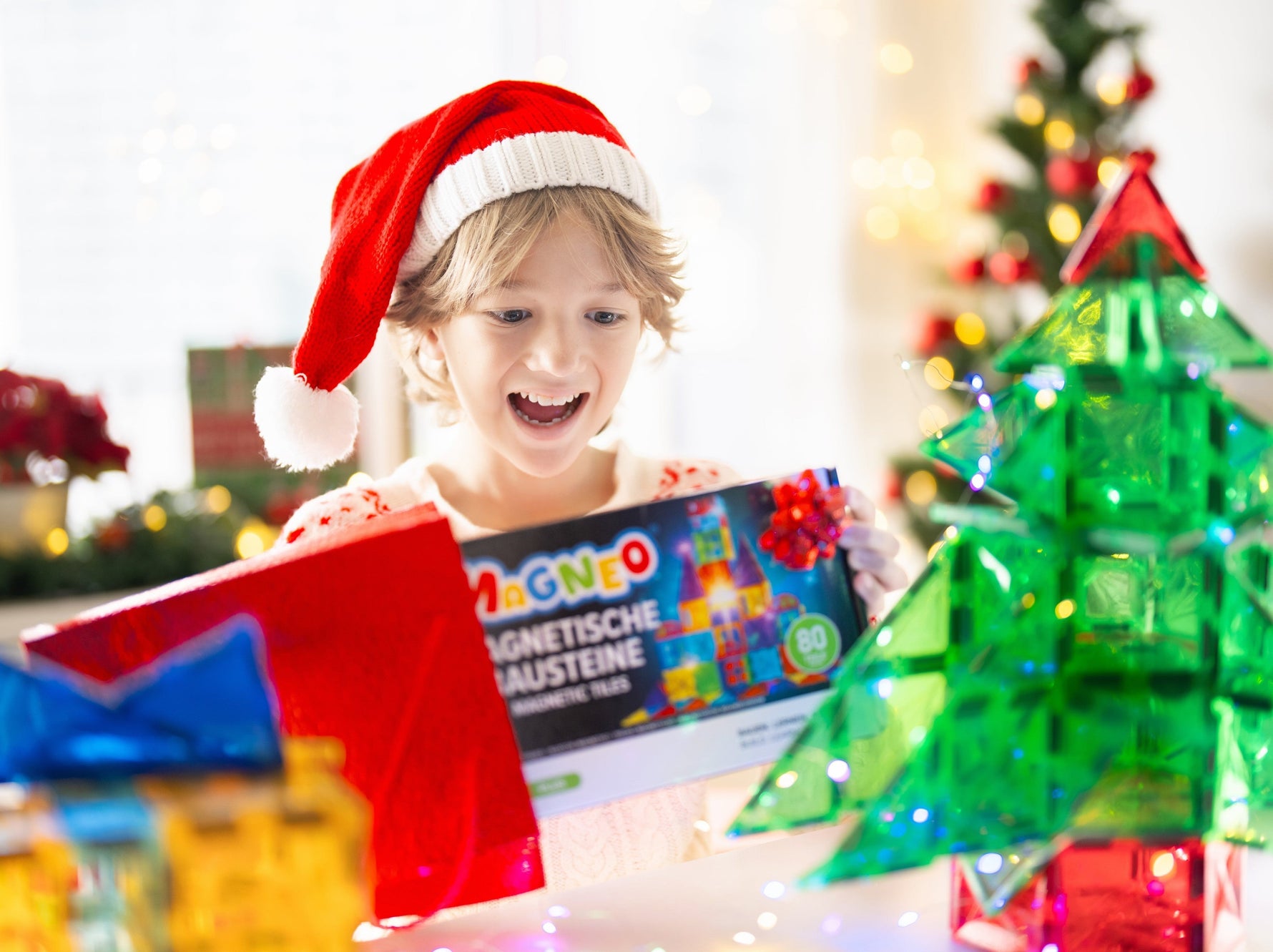 Kind spielt mit Magneo Magnetbausteinen in festlicher Weihnachtsumgebung.